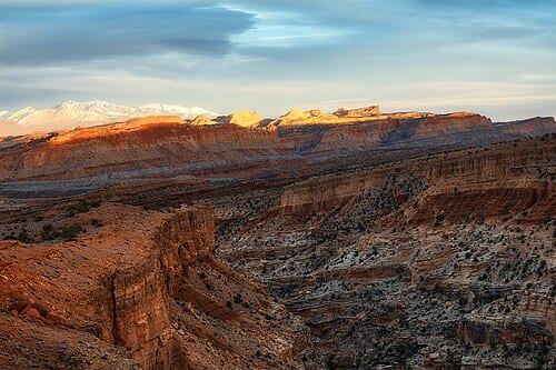 Rugged desert landscape glowing with an elevated band of sunset light, as seen & captured from Sunset Point in Capitol Reef National Park near Torrey, Utah (USA). This photo is offered under a standard <a href=" https://creativecommons.org/licenses/by/3.0/deed.en_US " rel="noreferrer…