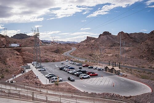 The Nevada-side visitor parking area serving the Mike O'Callaghan–Pat Tillman Memorial Bridge memorial plaza, with transmission towers and the winding approach road.