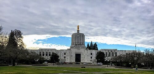 A panoramic photo of Oregon Capitol as blue skies poke through on a gray day