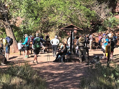 A large crowd gathers outside of the Manzanita Ranger station along the North Kaibab Trail. Many of these individuals are attempting a Rim to Rim hike, also known as R2R. For information on summer hiking in Grand Canyon National Park visit: <a…